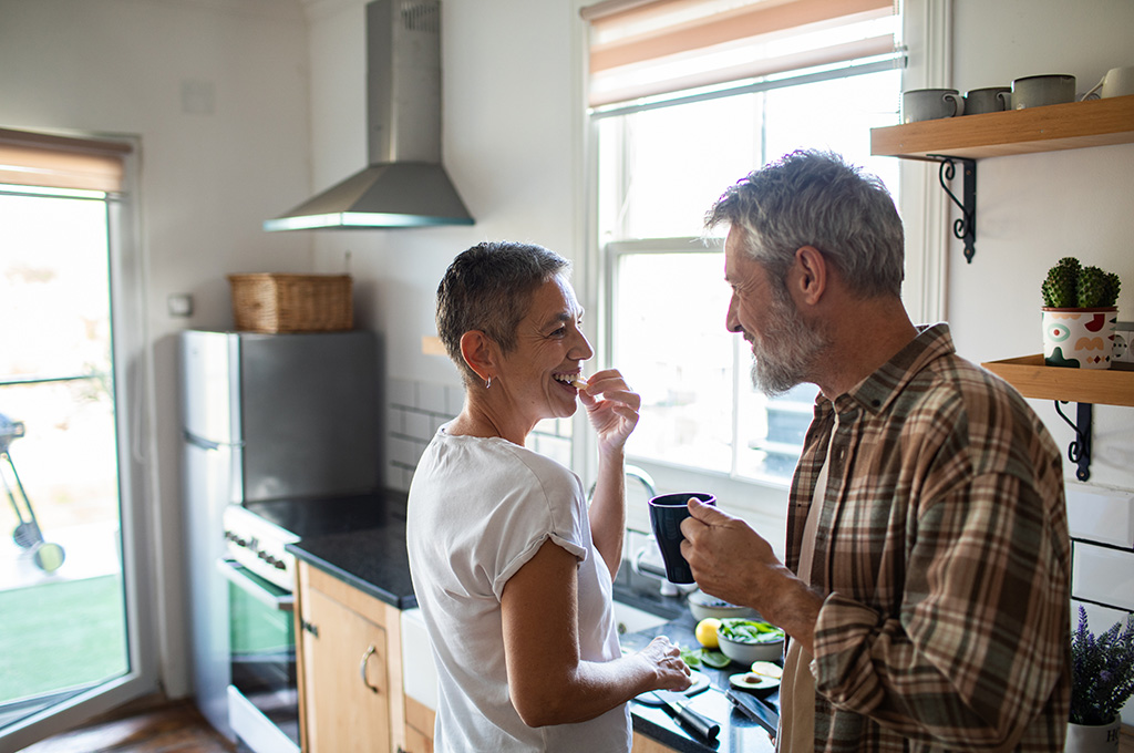 A veteran couple enjoying time together in the kitchen after exploring how to qualify for VA benefits