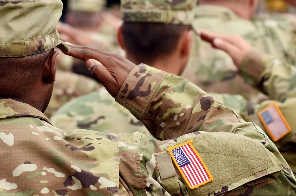 Army soldiers salute the flag while in formation