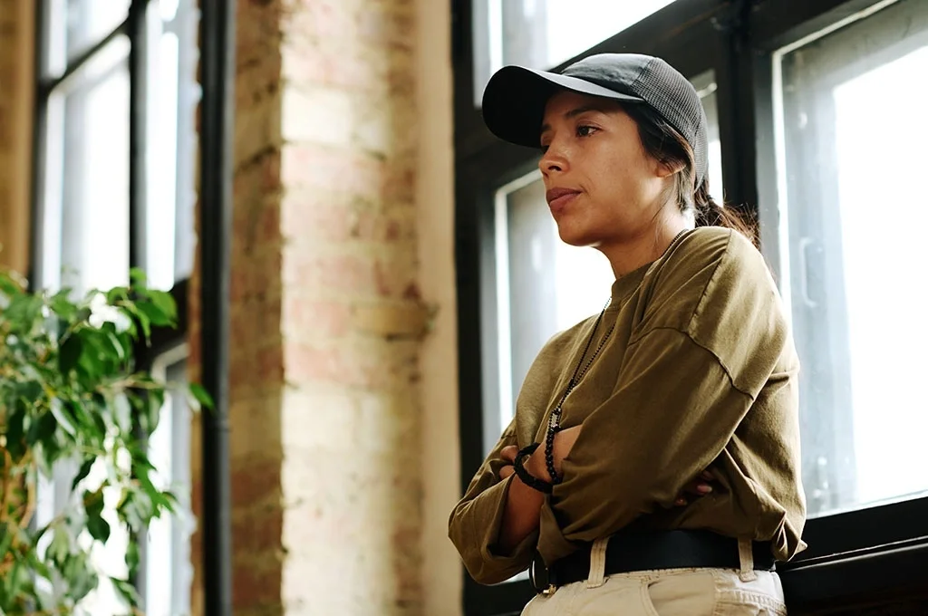A woman considers her options for veteran debt settlement standing next to a window