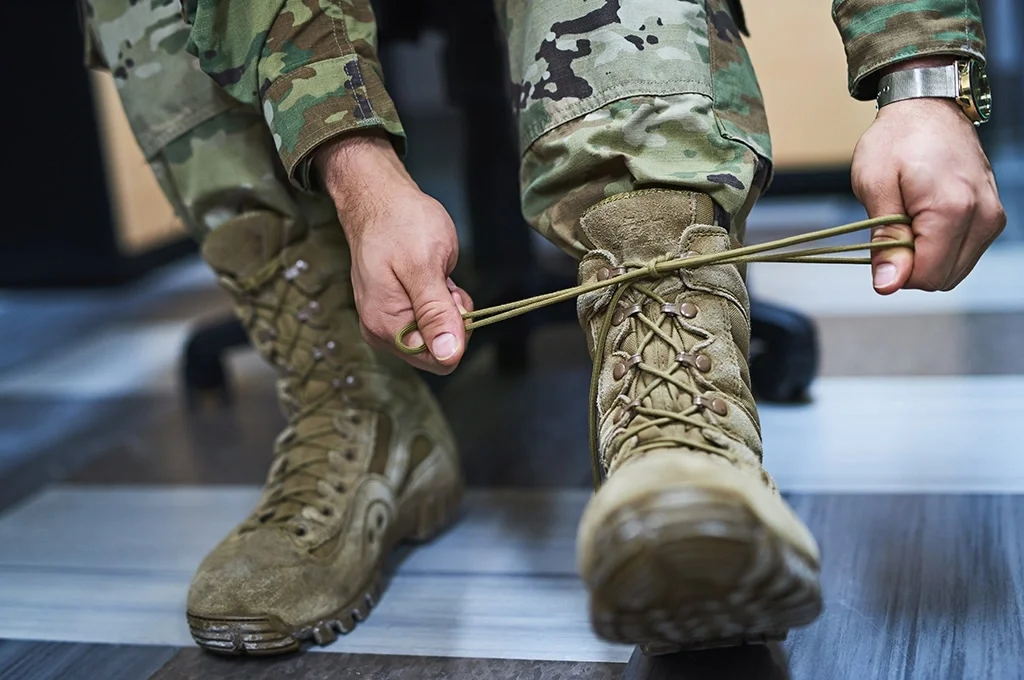 An Army soldier laces up his boots