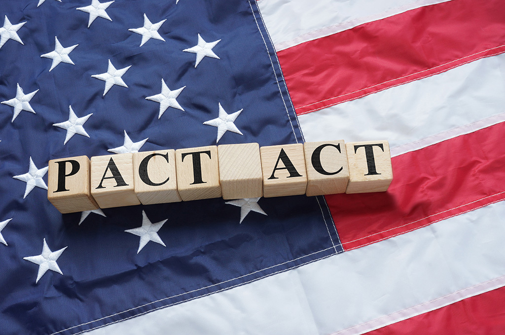 Scrabble letters spelling out PACT ACT sit atop an American flag