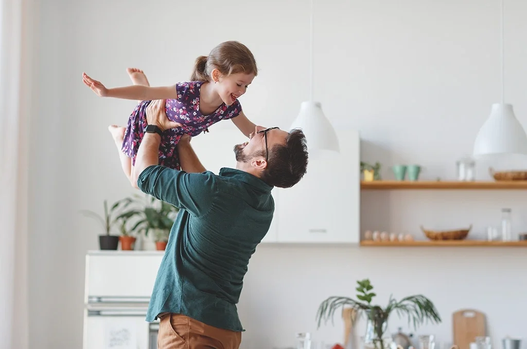 Veteran father lifting his daughter, laughing.